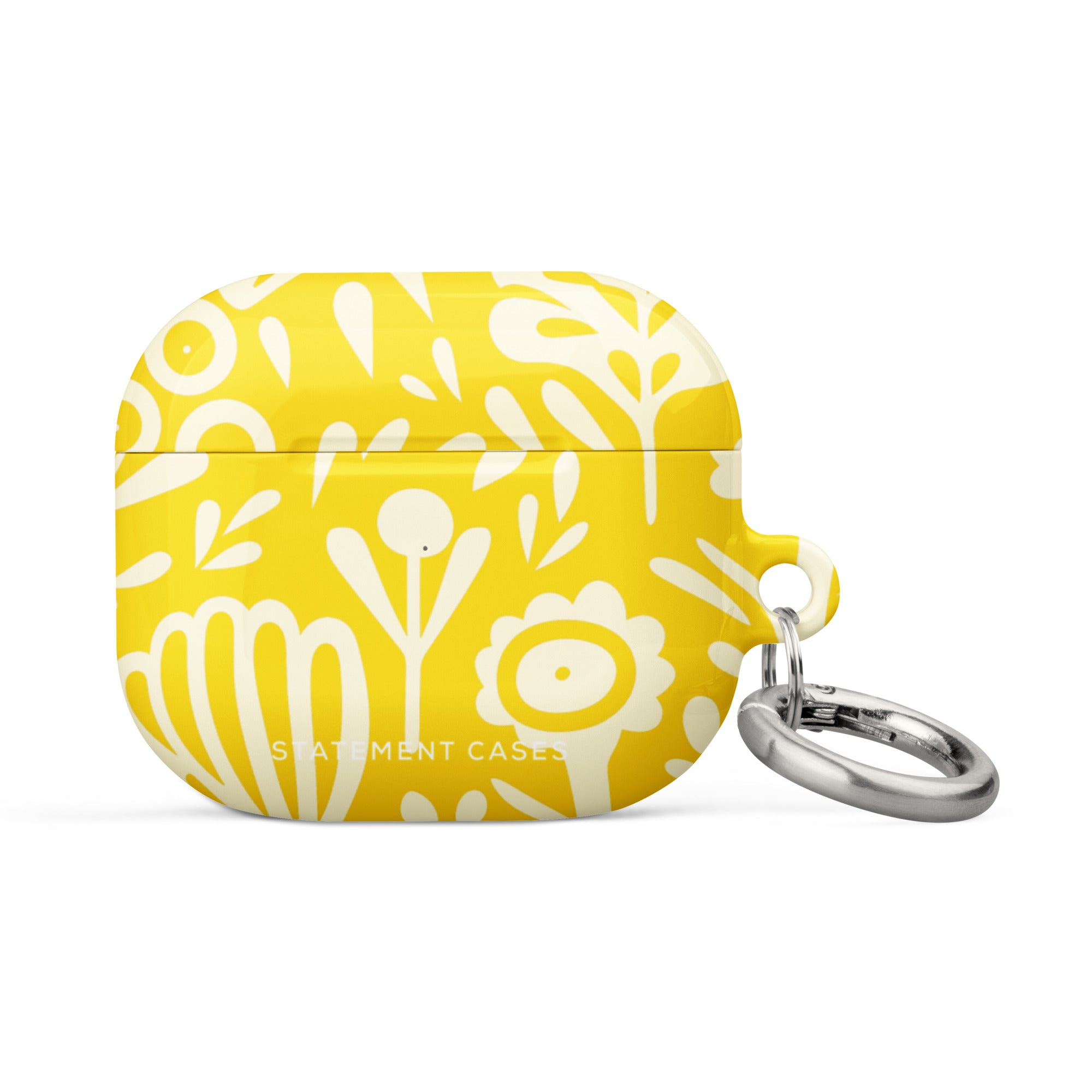 The Sol Dorado for AirPods Gen 3 by Statement Cases features a bright yellow design with white floral and abstract patterns. It offers a sturdy, impact-absorbing construction and comes with a metallic keyring on the right side for easy attachment to bags or keychains. The brand name "Statement Cases" is subtly printed on the front.