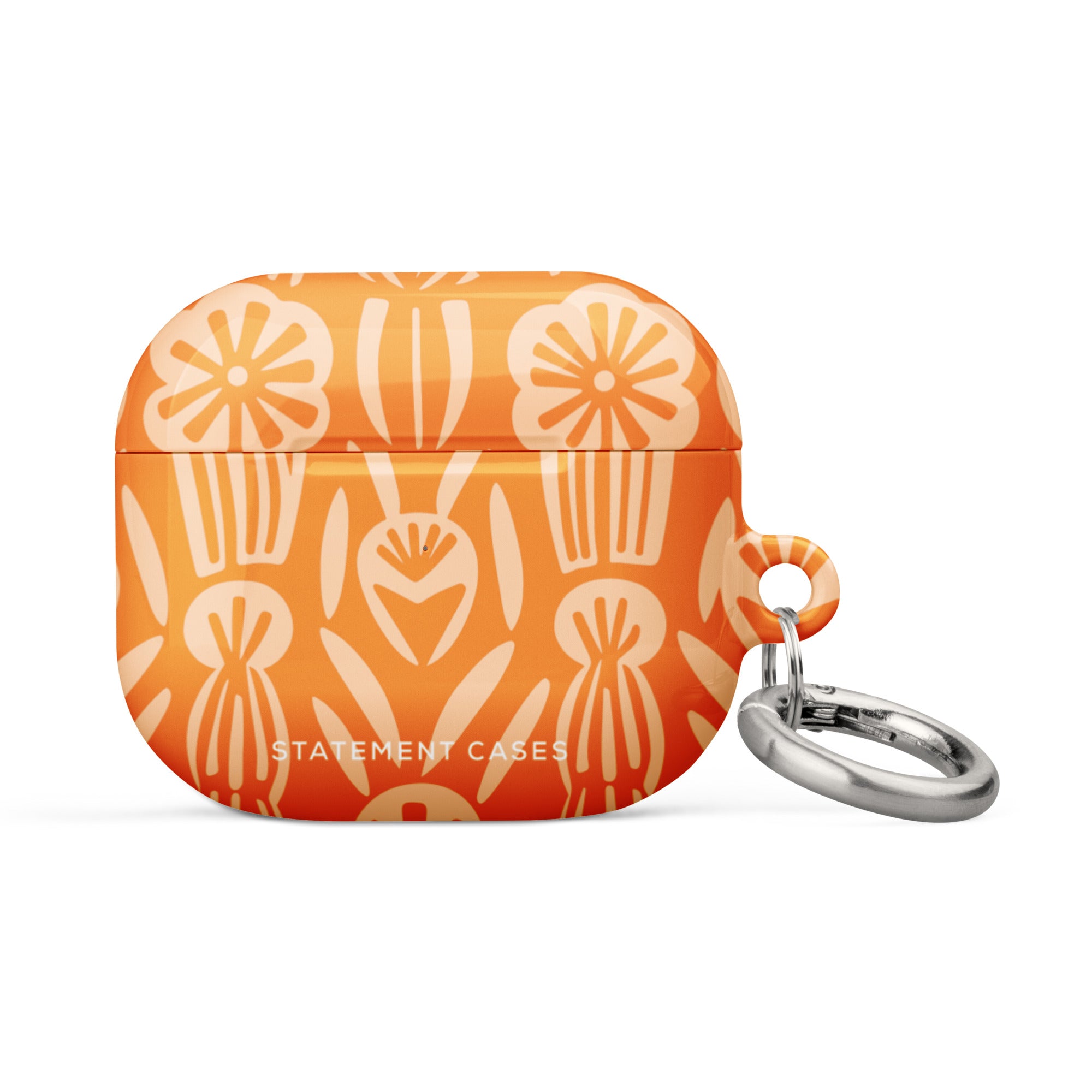 The Savannah Ardiente for AirPods Gen 3 by Statement Cases showcases a vibrant cream floral pattern set against an orange background. Crafted from premium impact-absorbing material, the design highlights abstract flowers and foliage. A small metal carabiner with a detachable keyring is affixed to the right side, and "STATEMENT CASES" is printed in white at the bottom.