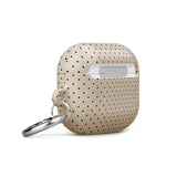 A beige, impact-absorbing Delicate Elegance for AirPods Gen 3 case with small black polka dots and a metal carabiner attachment on the side, featuring the brand name "Statement Cases" printed in white at the bottom.