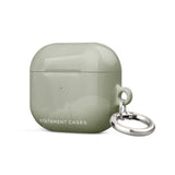 A Pistachio Haze for AirPods Gen 3 case with a silver metal carabiner attached to the right side, designed by Statement Cases. The case has a glossy finish and is crafted from premium impact-absorbing material for added protection.