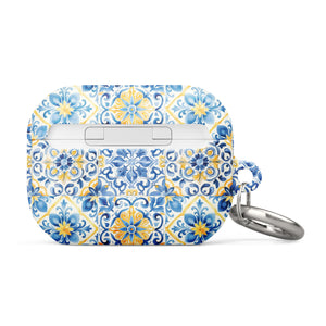 The Blue Mirage for AirPods Pro Gen 2 by Statement Cases is a decorative case for wireless earbuds, featuring an intricate blue and yellow tile pattern inspired by traditional Portuguese azulejos. This impact-absorbing case includes a small metal carabiner for easy attachment.