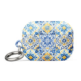 The Blue Mirage for AirPods Pro Gen 2 by Statement Cases is a decorative case for wireless earbuds, featuring an intricate blue and yellow tile pattern inspired by traditional Portuguese azulejos. This impact-absorbing case includes a small metal carabiner for easy attachment.