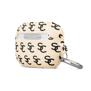 A beige hard shell Heritage Monogram for AirPods Pro Gen 2 case with a repeating black logo pattern, designed for impact-absorbing protection. It features a metal carabiner attached to the left side for convenience. The brand name "Statement Cases" is printed subtly at the bottom.