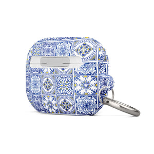 The Lisboa Azul for AirPods Pro Gen 2 by Statement Cases is a rectangular keychain pouch adorned with a blue and white tile pattern, featuring intricate floral and geometric motifs. Enhanced with impact-absorbing material, it doubles as an AirPods case. A metal carabiner is attached to the side for easy attachment to keys or other items.