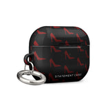 A stylish black case for AirPods Pro Gen 2 with a pattern of red high-heel shoes and the text "STATEMENT CASES" at the bottom. The impact-absorbing Saucy Stillettos by Statement Cases features a durable metal carabiner attached to the left side.