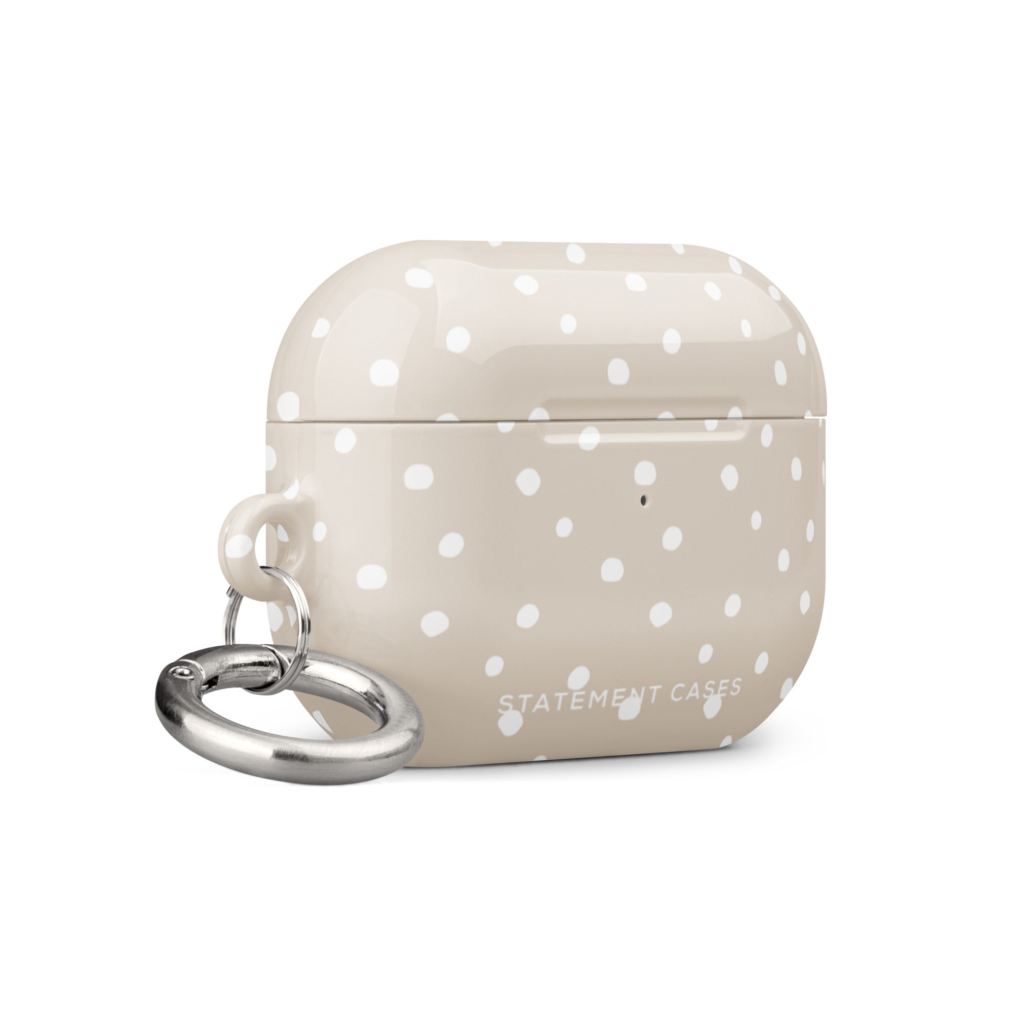 A beige Classic Nude for AirPods Pro Gen 2 case with white polka dots and a small metal carabiner attached to the side, displaying the brand text "Statement Cases.