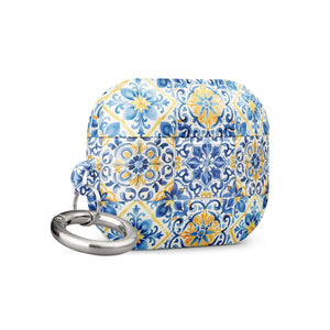 The Blue Mirage for AirPods Pro Gen 2 by Statement Cases is a decorative case for wireless earbuds, featuring an intricate blue and yellow tile pattern inspired by traditional Portuguese azulejos. This impact-absorbing case includes a small metal carabiner for easy attachment.