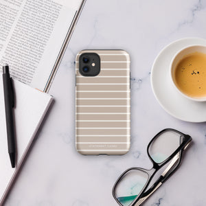 A smartphone with a beige and white striped, durable dual-layered case lays on a marble surface next to an open notebook, a black pen, a pair of black-rimmed eyeglasses, and a cup of coffee with foam. The phone case is branded "Statement Cases: Au Naturale for iPhone.