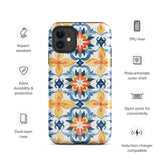 Statement Cases' Mediterranean Bloom for iPhone is showcased, featuring an intricate, colorful pattern. The design includes blue, yellow, and orange floral shapes in a symmetrical arrangement on a light blue background. This durable phone case provides dual-layer protection and is constructed from impact-resistant polycarbonate to safeguard your device.