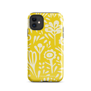 The Sol Dorado for iPhone by Statement Cases is a smartphone with a yellow case featuring a white, abstract floral and plant pattern. The camera lenses are prominent in the top left corner of the device. With dual-layer protection and impact-resistant TPU lining, "Statement Cases" is printed at the bottom of the case.