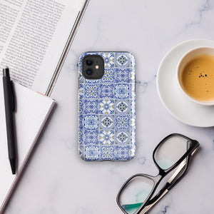 The Lisboa Azul for iPhone by Statement Cases is a smartphone adorned with a dual-layer protection phone case, featuring an intricate blue and white tile pattern. The design showcases various geometric and floral motifs, forming a visually appealing mosaic effect. The impact-resistant camera lenses and flash are prominently visible at the top left.