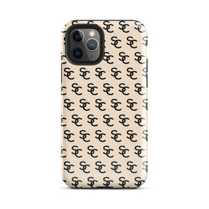 A beige protective iPhone case with an interlocking black "SC" pattern displayed across its back. Custom-tailored for the iPhone 15 Pro Max, the Heritage Monogram for iPhone by Statement Cases features cutouts for the camera lenses and buttons. The design is sleek and minimalistic.