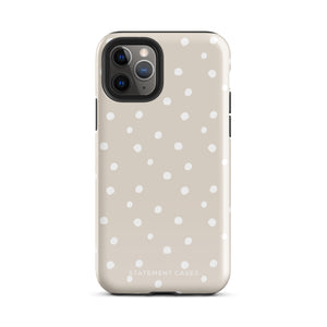 A beige Classic Nude for iPhone case with white polka dots, designed for the iPhone 15 Pro Max, covering the back of a phone with three visible camera lenses and one flash positioned at the upper left corner. This protective iPhone case features "Statement Cases" in small capital letters at the bottom.