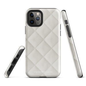 A smartphone with a textured, light gray Quilted Delight for iPhone protective case is shown. The case has a camera cutout that fits three lenses and a flash, with "Statement Cases" written at the bottom, perfectly tailored for the iPhone 15 Pro Max.