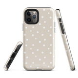 A beige Classic Nude for iPhone case with white polka dots, designed for the iPhone 15 Pro Max, covering the back of a phone with three visible camera lenses and one flash positioned at the upper left corner. This protective iPhone case features "Statement Cases" in small capital letters at the bottom.