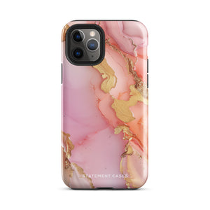 The Gold Blush Marble for iPhone showcases a glossy, marble-patterned case in shades of pink and gold. The decorative design features swirling patterns, seamlessly blending the colors. Crafted with impact-resistant polycarbonate for superior phone protection, "Statement Cases" is written in white at the bottom.