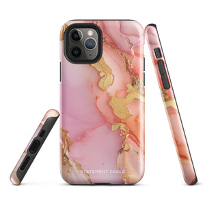 The Gold Blush Marble for iPhone showcases a glossy, marble-patterned case in shades of pink and gold. The decorative design features swirling patterns, seamlessly blending the colors. Crafted with impact-resistant polycarbonate for superior phone protection, "Statement Cases" is written in white at the bottom.