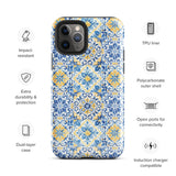 The Blue Mirage for iPhone by Statement Cases features a dual-layered, impact-resistant polycarbonate exterior with a TPU inner liner. Inspired by traditional Portuguese tiles, the blue and yellow patterned case boasts an intricate design of floral and geometric motifs. With its elegant and colorful appearance, the phone's camera is visible at the top left of the case.