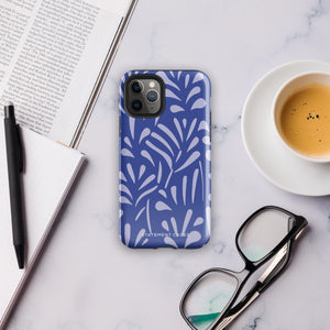 An iPhone encased in the "Mariposa Azul" by Statement Cases, featuring a blue design with an abstract white leaf pattern. The case combines curved and pointed shapes and provides dual-layer protection with TPU lining and impact-resistant polycarbonate. Camera lenses and other top elements remain unobstructed, and "Statement Cases" is inscribed at the bottom.