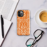 A Savannah Ardiente for iPhone from Statement Cases, featuring a dual-layered phone case in orange with a floral pattern showcasing cream-colored flowers, leaves, and geometric shapes. This impact-resistant polycarbonate case displays "STATEMENT CASES" at the bottom and reveals the camera lenses at the top left corner.