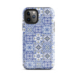 The Lisboa Azul for iPhone by Statement Cases is a smartphone adorned with a dual-layer protection phone case, featuring an intricate blue and white tile pattern. The design showcases various geometric and floral motifs, forming a visually appealing mosaic effect. The impact-resistant camera lenses and flash are prominently visible at the top left.