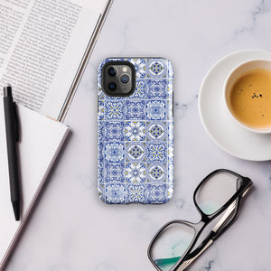 The Lisboa Azul for iPhone by Statement Cases is a smartphone adorned with a dual-layer protection phone case, featuring an intricate blue and white tile pattern. The design showcases various geometric and floral motifs, forming a visually appealing mosaic effect. The impact-resistant camera lenses and flash are prominently visible at the top left.