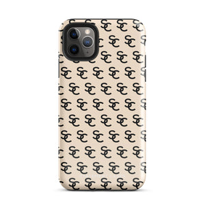 A beige protective iPhone case with an interlocking black "SC" pattern displayed across its back. Custom-tailored for the iPhone 15 Pro Max, the Heritage Monogram for iPhone by Statement Cases features cutouts for the camera lenses and buttons. The design is sleek and minimalistic.