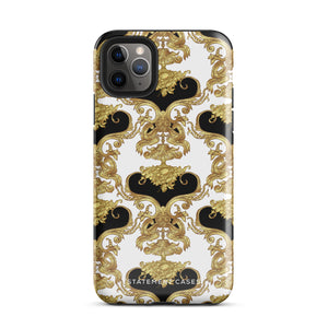 A protective iPhone 15 Pro Max case with a stylish design features an intricate gold and black baroque pattern. The camera lenses and logo branding "Statement Cases" are prominently visible.