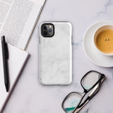 A protective iPhone case with a white marble-patterned design featuring three camera lenses and a flash. The marble pattern on this Marble Dreams for iPhone 15 Pro Max case is subtle, with light gray veining. The brand "Statement Cases" is subtly engraved at the bottom of the case.