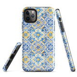 The Blue Mirage for iPhone by Statement Cases features a dual-layered, impact-resistant polycarbonate exterior with a TPU inner liner. Inspired by traditional Portuguese tiles, the blue and yellow patterned case boasts an intricate design of floral and geometric motifs. With its elegant and colorful appearance, the phone's camera is visible at the top left of the case.