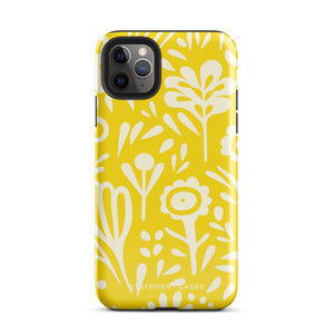 The Sol Dorado for iPhone by Statement Cases is a smartphone with a yellow case featuring a white, abstract floral and plant pattern. The camera lenses are prominent in the top left corner of the device. With dual-layer protection and impact-resistant TPU lining, "Statement Cases" is printed at the bottom of the case.