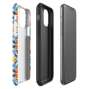 Statement Cases' Mediterranean Bloom for iPhone is showcased, featuring an intricate, colorful pattern. The design includes blue, yellow, and orange floral shapes in a symmetrical arrangement on a light blue background. This durable phone case provides dual-layer protection and is constructed from impact-resistant polycarbonate to safeguard your device.