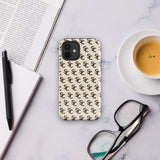 A beige protective iPhone case with an interlocking black "SC" pattern displayed across its back. Custom-tailored for the iPhone 15 Pro Max, the Heritage Monogram for iPhone by Statement Cases features cutouts for the camera lenses and buttons. The design is sleek and minimalistic.