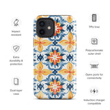 Statement Cases' Mediterranean Bloom for iPhone is showcased, featuring an intricate, colorful pattern. The design includes blue, yellow, and orange floral shapes in a symmetrical arrangement on a light blue background. This durable phone case provides dual-layer protection and is constructed from impact-resistant polycarbonate to safeguard your device.