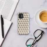 A beige protective iPhone case with an interlocking black "SC" pattern displayed across its back. Custom-tailored for the iPhone 15 Pro Max, the Heritage Monogram for iPhone by Statement Cases features cutouts for the camera lenses and buttons. The design is sleek and minimalistic.