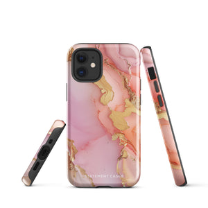 The Gold Blush Marble for iPhone showcases a glossy, marble-patterned case in shades of pink and gold. The decorative design features swirling patterns, seamlessly blending the colors. Crafted with impact-resistant polycarbonate for superior phone protection, "Statement Cases" is written in white at the bottom.