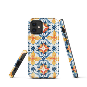 Statement Cases' Mediterranean Bloom for iPhone is showcased, featuring an intricate, colorful pattern. The design includes blue, yellow, and orange floral shapes in a symmetrical arrangement on a light blue background. This durable phone case provides dual-layer protection and is constructed from impact-resistant polycarbonate to safeguard your device.