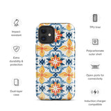 Statement Cases' Mediterranean Bloom for iPhone is showcased, featuring an intricate, colorful pattern. The design includes blue, yellow, and orange floral shapes in a symmetrical arrangement on a light blue background. This durable phone case provides dual-layer protection and is constructed from impact-resistant polycarbonate to safeguard your device.