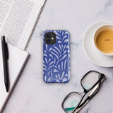 An iPhone encased in the "Mariposa Azul" by Statement Cases, featuring a blue design with an abstract white leaf pattern. The case combines curved and pointed shapes and provides dual-layer protection with TPU lining and impact-resistant polycarbonate. Camera lenses and other top elements remain unobstructed, and "Statement Cases" is inscribed at the bottom.