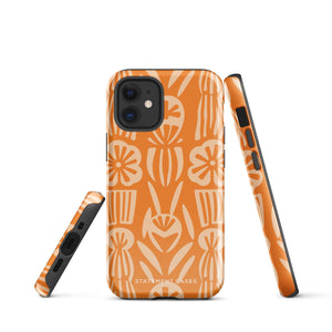 A Savannah Ardiente for iPhone from Statement Cases, featuring a dual-layered phone case in orange with a floral pattern showcasing cream-colored flowers, leaves, and geometric shapes. This impact-resistant polycarbonate case displays "STATEMENT CASES" at the bottom and reveals the camera lenses at the top left corner.