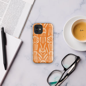 A Savannah Ardiente for iPhone from Statement Cases, featuring a dual-layered phone case in orange with a floral pattern showcasing cream-colored flowers, leaves, and geometric shapes. This impact-resistant polycarbonate case displays "STATEMENT CASES" at the bottom and reveals the camera lenses at the top left corner.