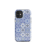 The Lisboa Azul for iPhone by Statement Cases is a smartphone adorned with a dual-layer protection phone case, featuring an intricate blue and white tile pattern. The design showcases various geometric and floral motifs, forming a visually appealing mosaic effect. The impact-resistant camera lenses and flash are prominently visible at the top left.