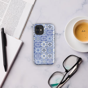 The Lisboa Azul for iPhone by Statement Cases is a smartphone adorned with a dual-layer protection phone case, featuring an intricate blue and white tile pattern. The design showcases various geometric and floral motifs, forming a visually appealing mosaic effect. The impact-resistant camera lenses and flash are prominently visible at the top left.