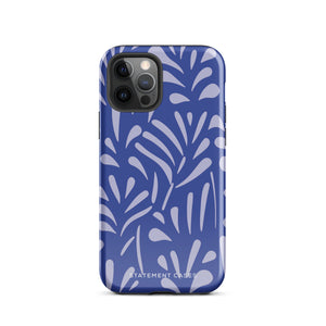 An iPhone encased in the "Mariposa Azul" by Statement Cases, featuring a blue design with an abstract white leaf pattern. The case combines curved and pointed shapes and provides dual-layer protection with TPU lining and impact-resistant polycarbonate. Camera lenses and other top elements remain unobstructed, and "Statement Cases" is inscribed at the bottom.