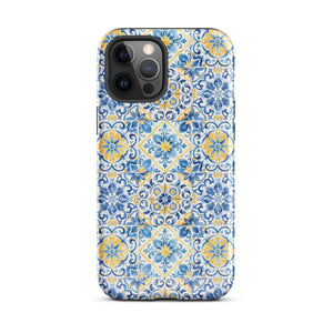 The Blue Mirage for iPhone by Statement Cases features a dual-layered, impact-resistant polycarbonate exterior with a TPU inner liner. Inspired by traditional Portuguese tiles, the blue and yellow patterned case boasts an intricate design of floral and geometric motifs. With its elegant and colorful appearance, the phone's camera is visible at the top left of the case.