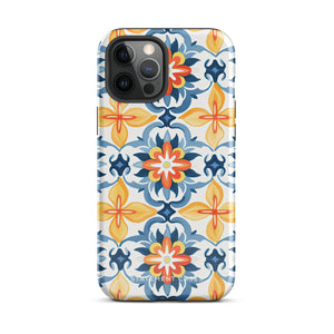 Statement Cases' Mediterranean Bloom for iPhone is showcased, featuring an intricate, colorful pattern. The design includes blue, yellow, and orange floral shapes in a symmetrical arrangement on a light blue background. This durable phone case provides dual-layer protection and is constructed from impact-resistant polycarbonate to safeguard your device.