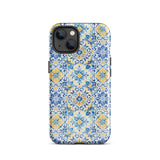 The Blue Mirage for iPhone by Statement Cases features a dual-layered, impact-resistant polycarbonate exterior with a TPU inner liner. Inspired by traditional Portuguese tiles, the blue and yellow patterned case boasts an intricate design of floral and geometric motifs. With its elegant and colorful appearance, the phone's camera is visible at the top left of the case.