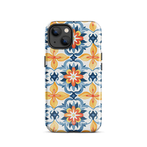 Statement Cases' Mediterranean Bloom for iPhone is showcased, featuring an intricate, colorful pattern. The design includes blue, yellow, and orange floral shapes in a symmetrical arrangement on a light blue background. This durable phone case provides dual-layer protection and is constructed from impact-resistant polycarbonate to safeguard your device.