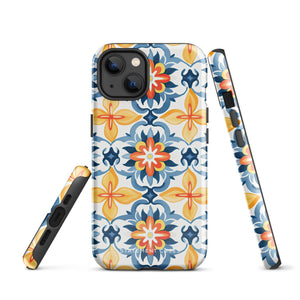 Statement Cases' Mediterranean Bloom for iPhone is showcased, featuring an intricate, colorful pattern. The design includes blue, yellow, and orange floral shapes in a symmetrical arrangement on a light blue background. This durable phone case provides dual-layer protection and is constructed from impact-resistant polycarbonate to safeguard your device.