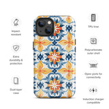 Statement Cases' Mediterranean Bloom for iPhone is showcased, featuring an intricate, colorful pattern. The design includes blue, yellow, and orange floral shapes in a symmetrical arrangement on a light blue background. This durable phone case provides dual-layer protection and is constructed from impact-resistant polycarbonate to safeguard your device.